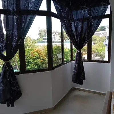 a room with two windows with blue curtains at Risma Homestay in Batu Ferringhi