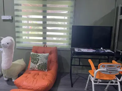 a living room with an orange chair and a tv at Kerlingfornia Kiddo Kingdom in Kerling