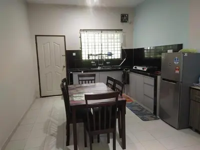 a kitchen with a table and chairs and a refrigerator at Teratak Desa Cemerlang 1