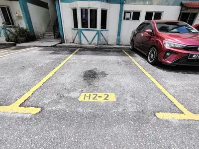a car parked in a parking lot next to a building at Puncak Cameron Holiday in Cameron Highlands