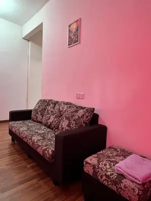 a couch and a ottoman in a room with a pink wall at Highland Breze Homestay in Tanah Rata