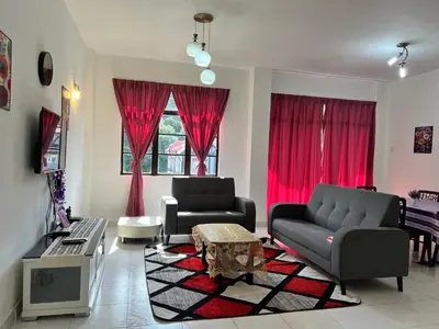 a living room with two couches and red curtains at Highland Breze Homestay in Tanah Rata