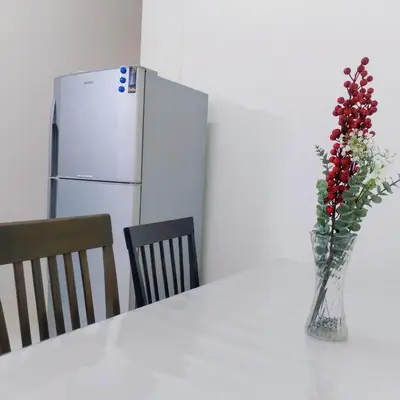 a vase with red berries in it on a table with a refrigerator at 10min near Ipoh Town Family Old & New Style 8Px in Ipoh