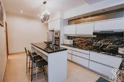 a kitchen with white cabinets and granite counter tops at Luxe Retreat Homestay by Verve in Ipoh