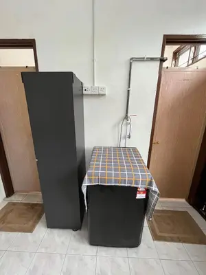 a black refrigerator and a table in a room at Santai DPermai Homestay in Selama