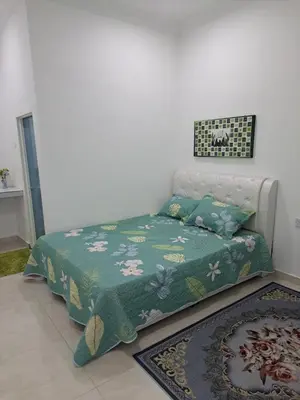 a bedroom with a bed with a green comforter at Teratak Sumayyah 2 - For Islam only - Pondok Lenggong in Kampong Banggol Belimbing