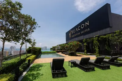 a hotel with chairs and a pool in front of a building at Beacon Executive Suite in Jalan Sungai Pinang George Town in George Town