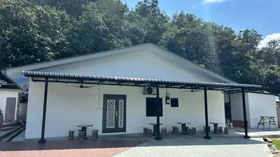a white building with picnic tables in front of it at Kuala Kubu Bharu Guesthouse Hotel in Kuala Kubu Baharu