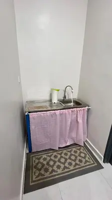 a sink in a corner of a room with a table at Kuala Kubu Bharu Guesthouse Hotel in Kuala Kubu Baharu