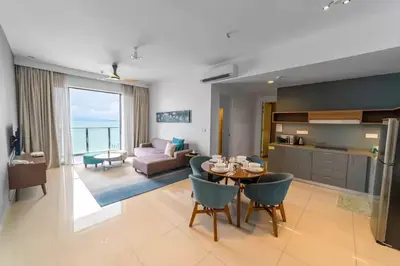 a kitchen and a living room with a table and chairs at Seaview Studio 2BR 3BR Tanjung Point Residences in Tanjong Tokong