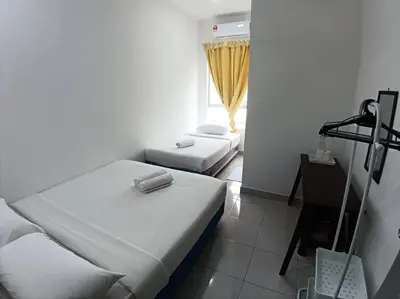 a small room with two beds and a desk at Raub Sutera Homestay in Kampong Sempalit Ulu
