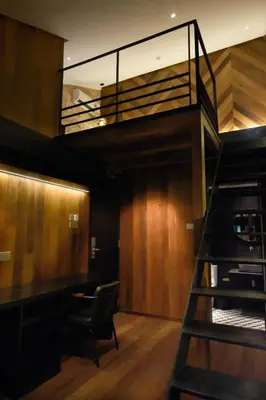 a staircase in a room with a desk and a chair at Playce Hotel in George Town