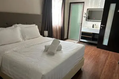 a bedroom with a white bed with a sink and a mirror at King's Lane in Ipoh