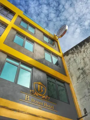 a yellow and gray building with a clock on top at B Street Hotel in George Town