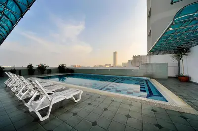 a pool on the roof of a building with lounge chairs at Hotel Continental Penang in George Town