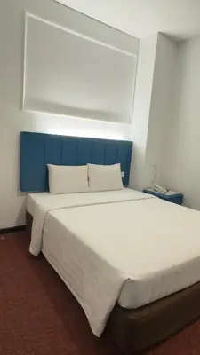 a large white bed with a blue headboard in a room at Hotel Continental Penang in George Town