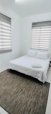 a bed in a white room with two windows at HomestayFA in Gua Sai