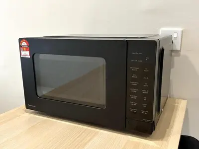 a black microwave oven sitting on a wooden shelf at Relaxstay Anderson Residences, Family Friendly 6px 2br in Ipoh