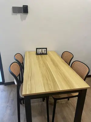 a clock sitting on top of a wooden table with chairs at Hafiyya Raintown Homestay, Taiping in Taiping