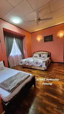 two beds in a room with orange walls at Afnaz Homestay Penang in Perai