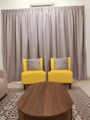 a living room with two yellow chairs and a table at Residensi Seri Serindit Melaka in Gua Sai