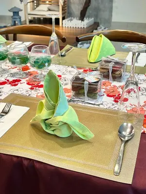 a table with a green napkin and glasses on it at Cheekaaboo Playhouse Ipoh I Private Pool Family Stay with Indoor Playzone in Ipoh