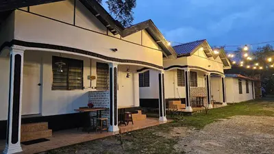 a white house with a deck with chairs on it at Batu Puteh Chalet by the River, Pool, WIFI