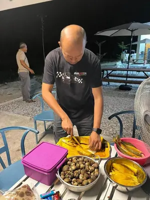 a man preparing food on a table with a plate of food at The Canal Villa in Sungai Besar
