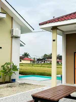 a patio with a wooden bench in front of a house at The Canal Villa in Sungai Besar