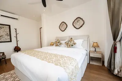 a bedroom with a white bed and two clocks on the wall at Coconut Bay beach Villa seaview karaoke 20pax in Tanjung Bungah