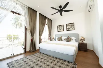 a bedroom with a bed and a ceiling fan at Coconut Bay beach Villa seaview karaoke 20pax in Tanjung Bungah