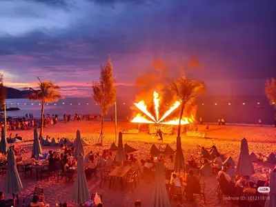 a crowd of people on a beach with a fire show at Batu Ferringhi Sri Sayang Resort in Batu Ferringhi