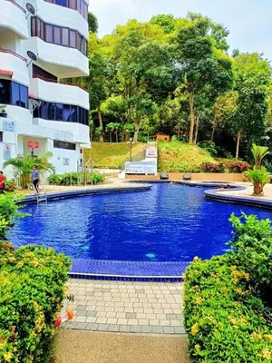a large blue swimming pool next to a building at Batu Ferringhi Sri Sayang Resort in Batu Ferringhi
