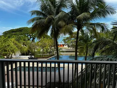 a view of a pool from a balcony with palm trees at Azure Haven - Seaview Resort Home, By the Sea Batu Ferringhi in Batu Ferringhi