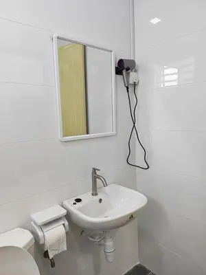 a white bathroom with a sink and a mirror at Cozy Haven \u6696\u5fc3\u5c45 in Simpang Ampat