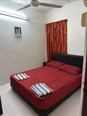 a bedroom with a bed with red sheets and a window at YDK Homestay in Padang Rengas