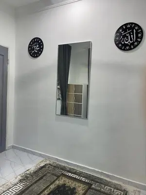 a mirror on a white wall with two plates and a rug at D'Savanna Homestay Gerik in Gua Sai