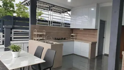 a kitchen with white cabinets and a table with chairs at D'Savanna Homestay Gerik in Gua Sai