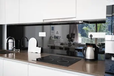 a kitchen with white cabinets and a living room at By The Sea Haven 2BR 6pax in Batu Ferringhi