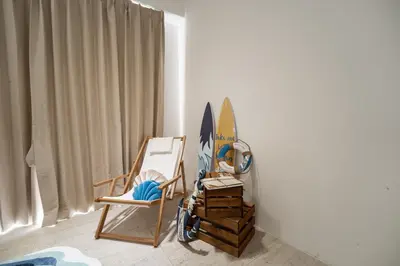 a room with a chair and a surfboard against a wall at By The Sea Haven 2BR 6pax in Batu Ferringhi