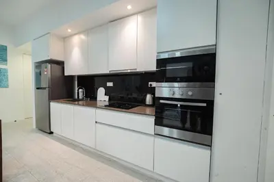 a kitchen with white cabinets and stainless steel appliances at By The Sea Haven 2BR 6pax in Batu Ferringhi
