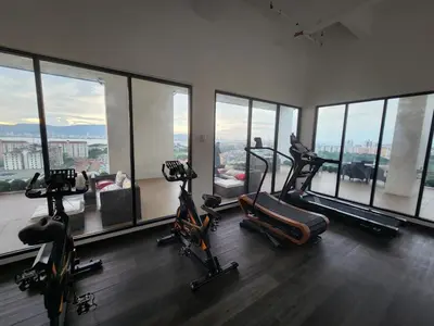 a gym with treadmills and exercise bikes in a room with windows at Praicon Tower Hotel Large Suite 3BR - Butterworth in Butterworth