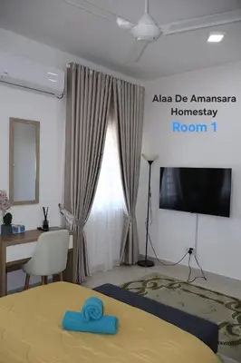 a bedroom with a bed and a desk and a television at Alaa De Amansara Homestay in Kepala Batas