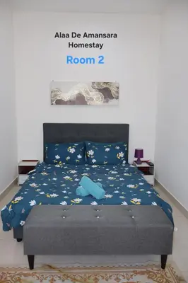a bedroom with a bed with a blue comforter at Alaa De Amansara Homestay in Kepala Batas