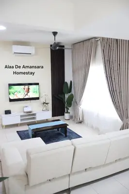 a living room with a white couch and a tv at Alaa De Amansara Homestay in Kepala Batas