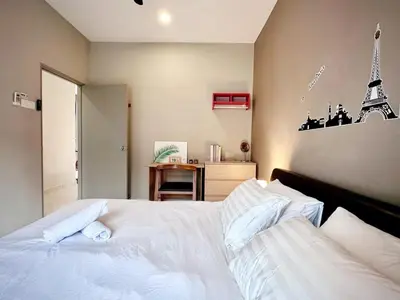 a bedroom with a white bed with a eiffel tower on the wall at Charming 4BR Family House Quite Area & Cozy in Simpang Ampat