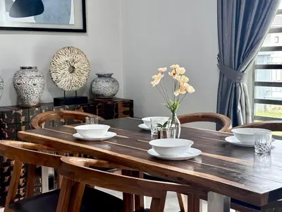 a wooden table with chairs and bowls and flowers on it at Charming 4BR Family House Quite Area & Cozy in Simpang Ampat