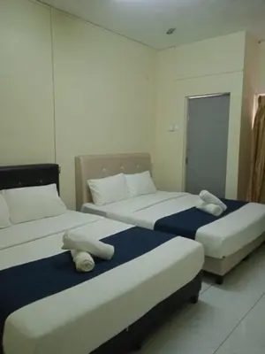 two beds in a hotel room with towels on them at Rest N Go CH in Tanah Rata