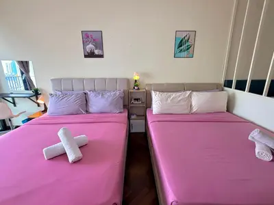 two beds in a room with pink sheets and teddy bears at Landmark Seaview Cozy Family Suite with Balcony 6 Pax in Tanjong Tokong