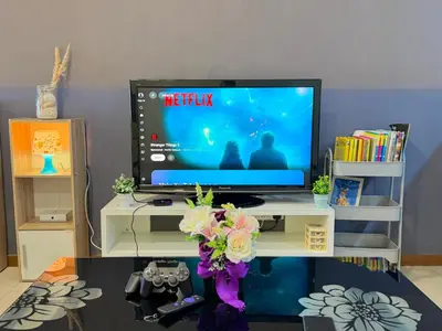 a tv sitting on top of a white table with flowers at Landmark Seaview Cozy Family Suite with Balcony 6 Pax in Tanjong Tokong